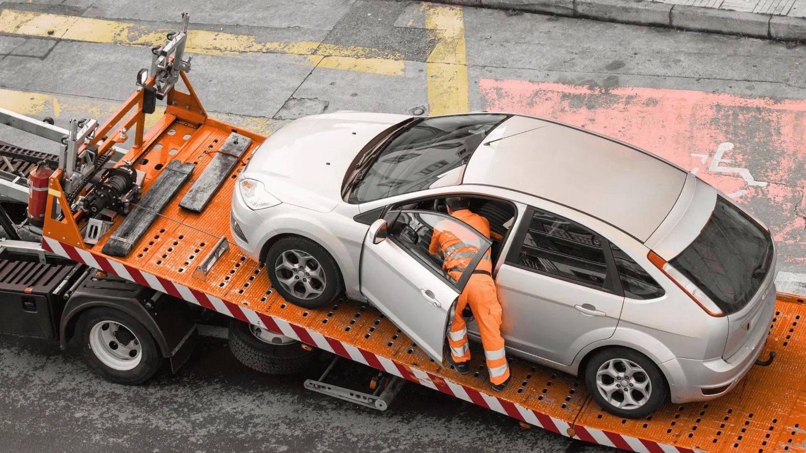 Car secured on an orange flatbed tow truck