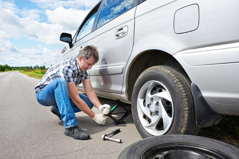 Changing a flat tire at the roadside with a jack and a spare